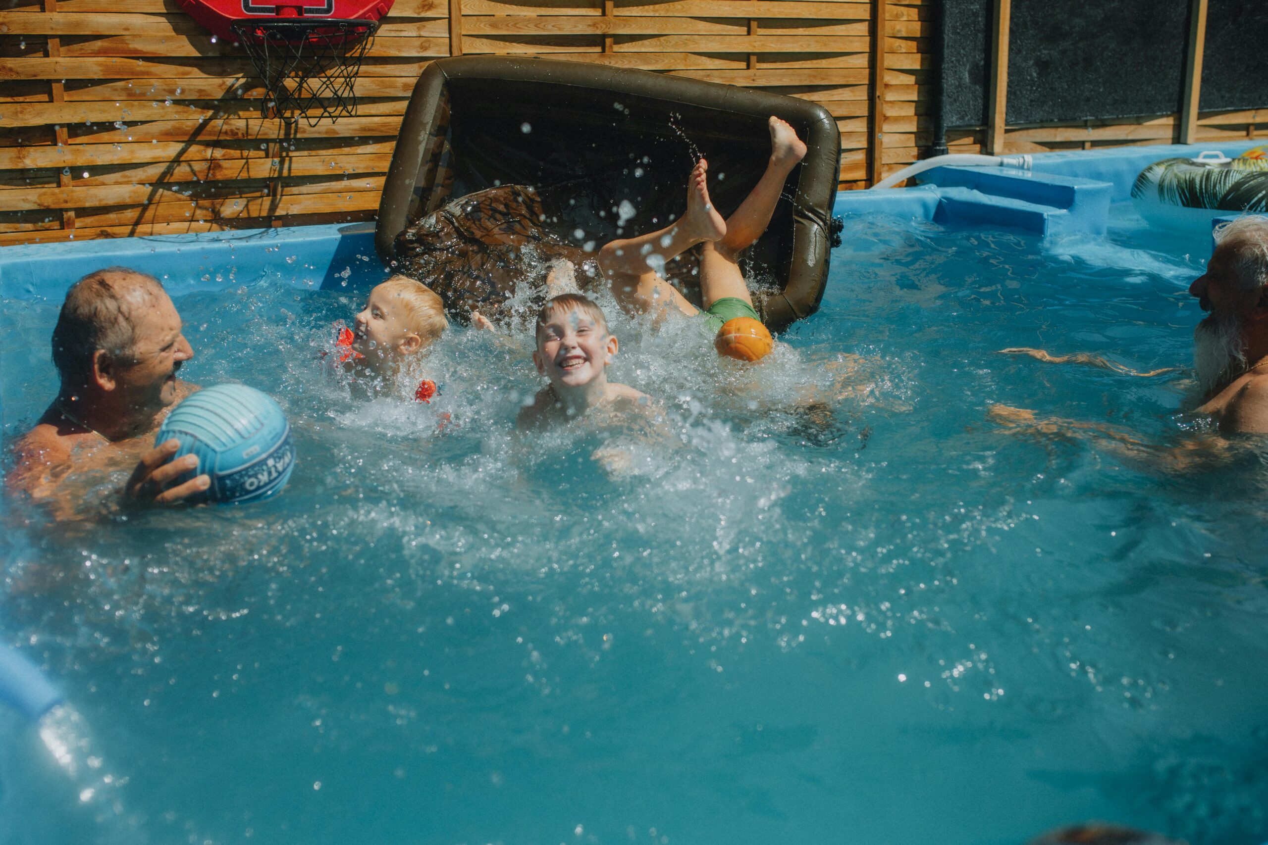 A Few Kids Play Games With Older Adults In A Swimming Pool.